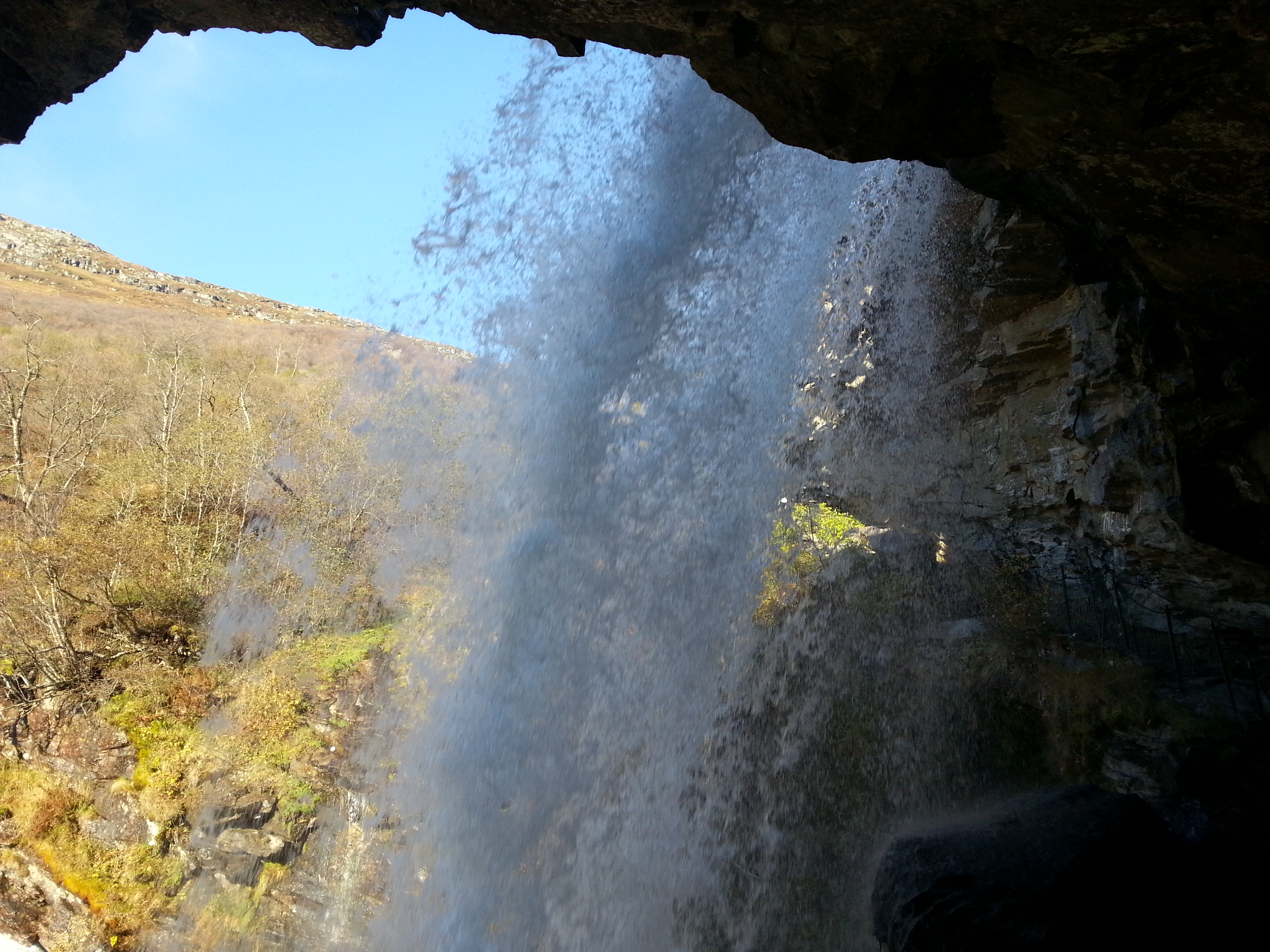 Walking behind Storsæterfossen waterfall in Geiranger in Norway