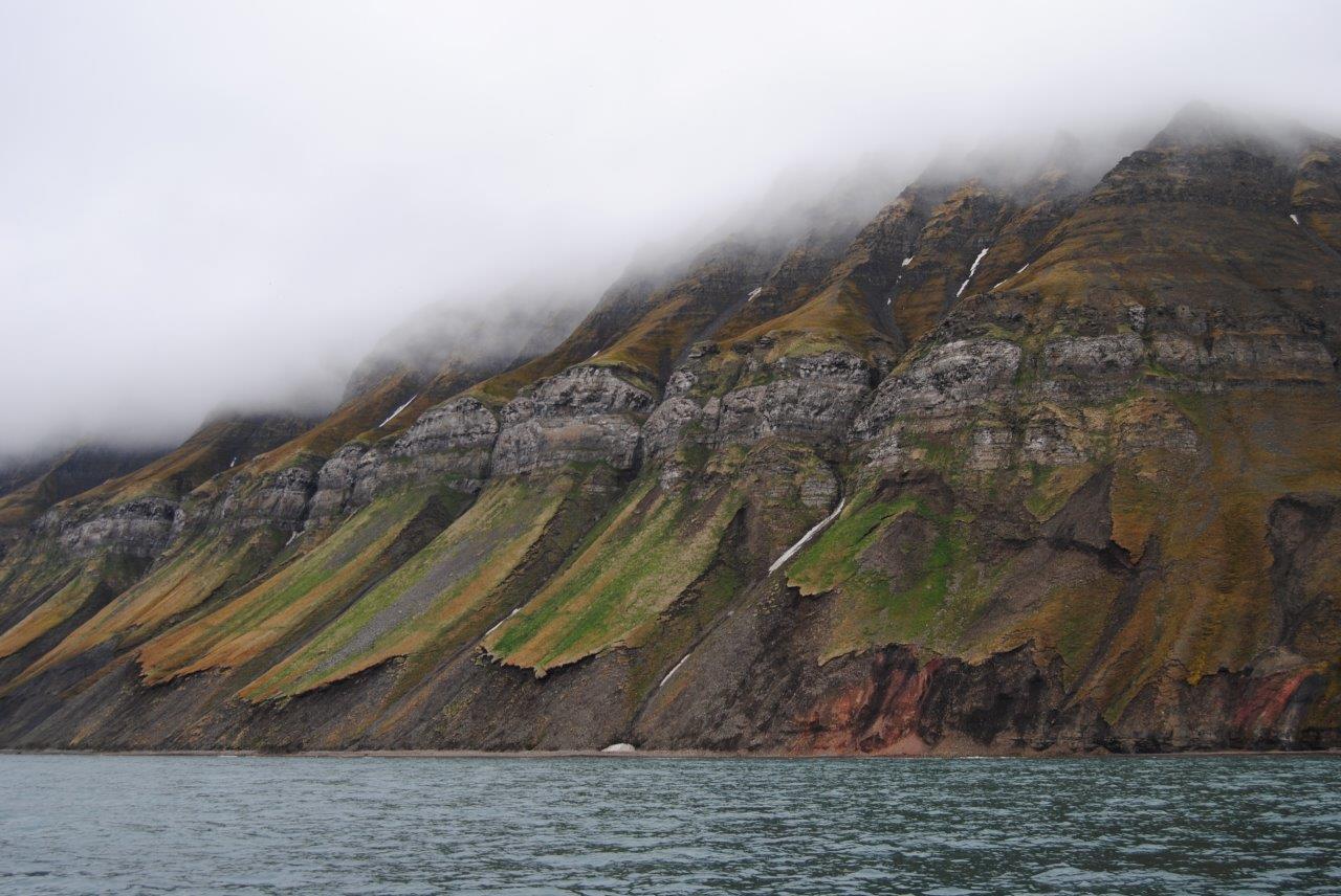 The fog is hanging low down the mountainside. Svalbard, Norway.